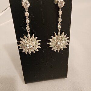 Dangle silver tone crystal earrings in star or sunburst shape